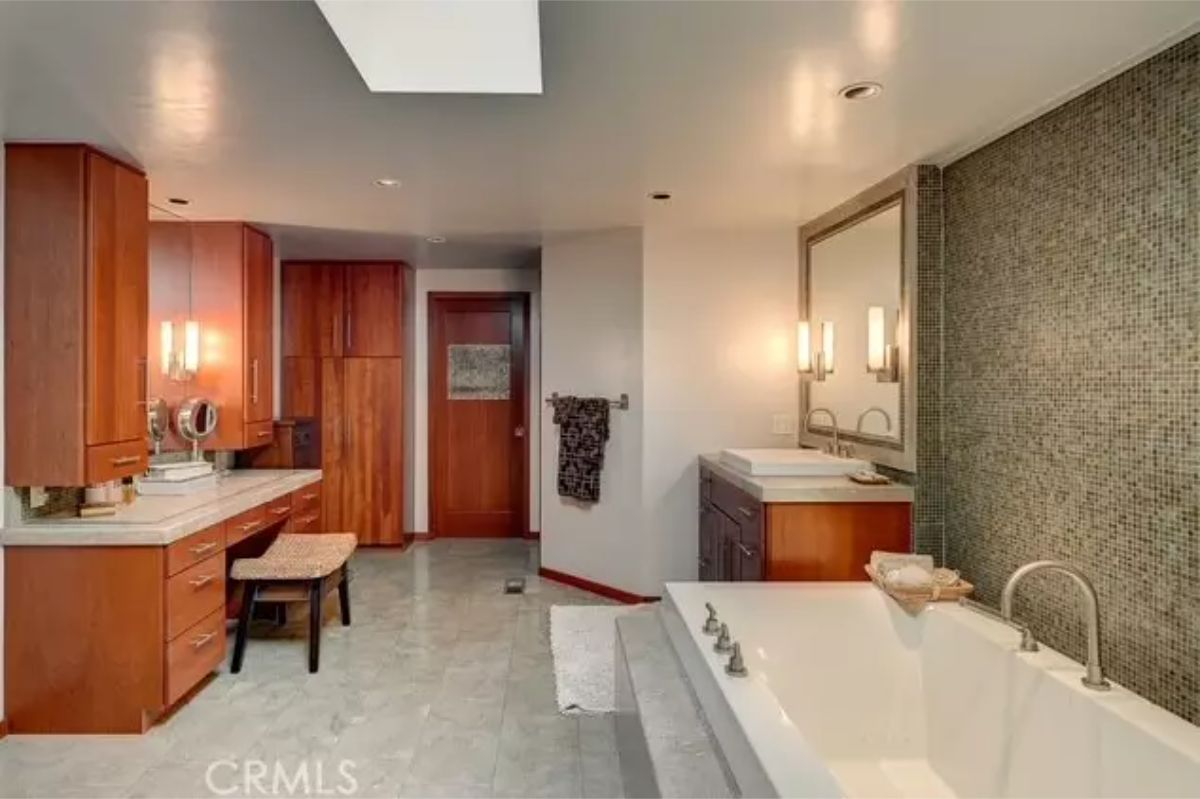 Bathroom has a large rectangular soaking tub next to a textured accent wall.