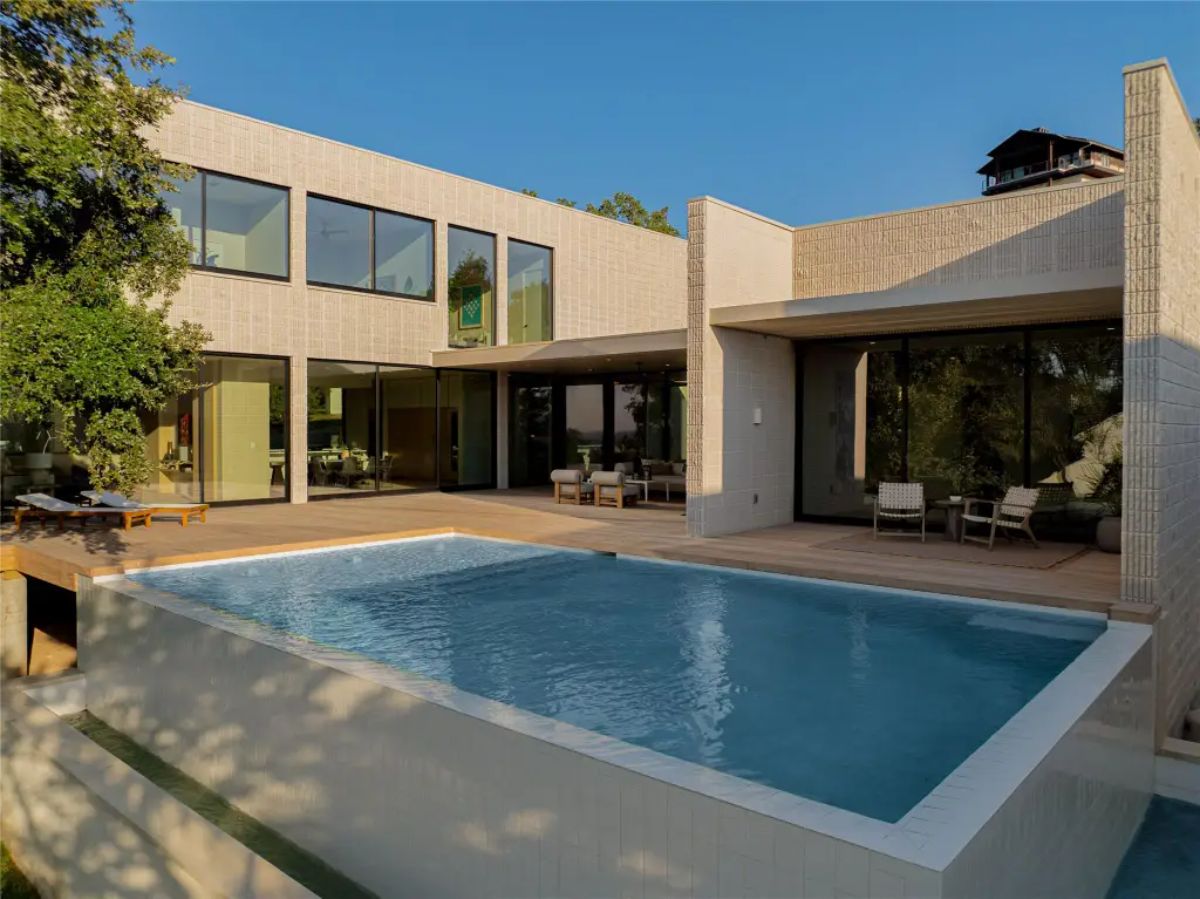 Stunning modern pool area surrounded by sleek architecture, warm wood decking, and lush greenery. 