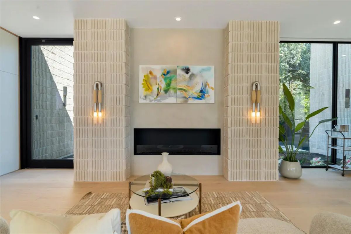 Beautifully designed fireplace wall with textured panels, contemporary artwork, and soft accent lighting. 