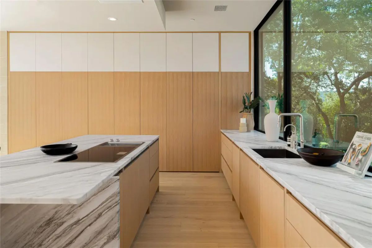 Contemporary kitchen with warm wood cabinetry, elegant marble countertops, and a clean minimalist aesthetic. 
