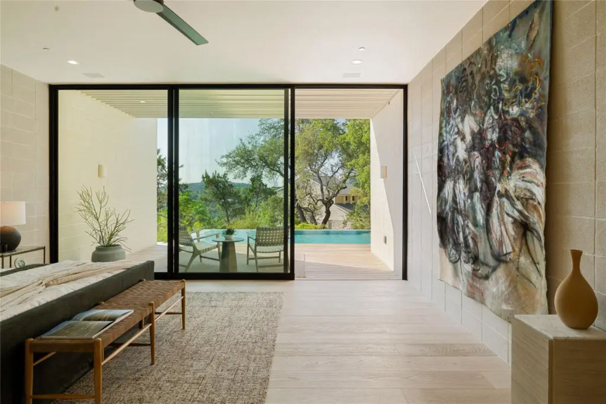 Elegant bedroom view featuring a large abstract painting, warm natural tones, and seamless indoor-outdoor flow. 
