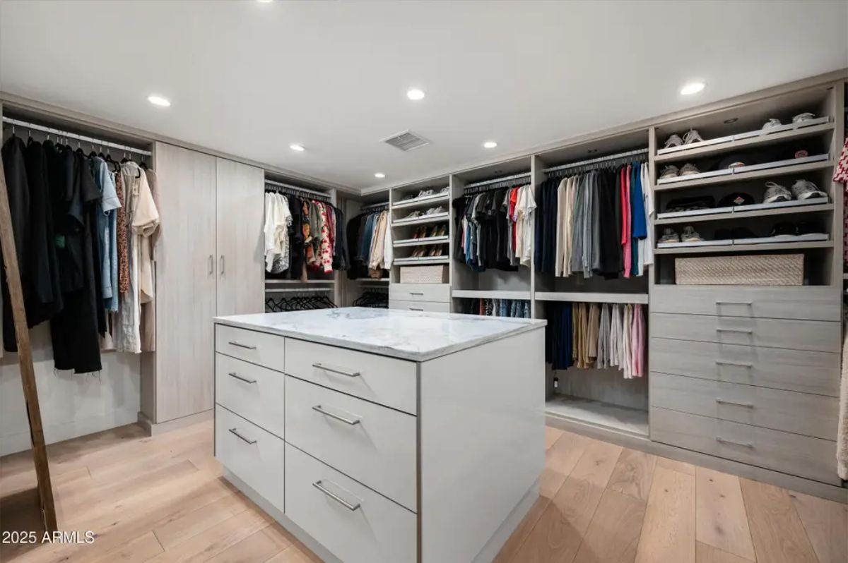 Walk-in closet with built-in shelving, a central island, and well-organized storage for clothes and accessories. 