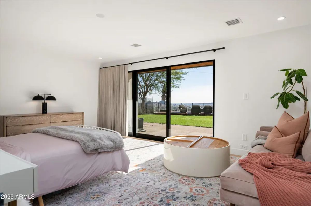 Cozy guest bedroom with a soft color palette, outdoor access, and a lounge area for relaxation. 