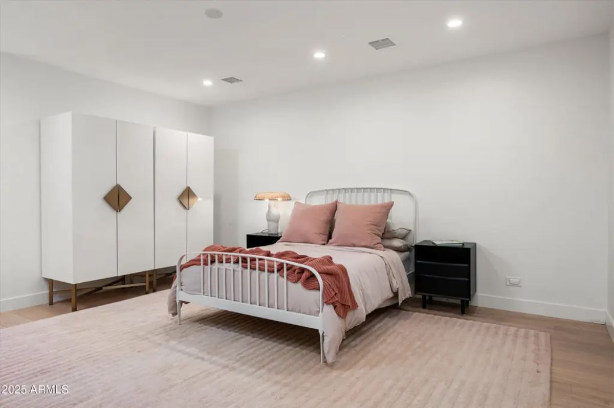 Another bedroom with a vintage-inspired bed frame, blush pink accents, and minimalist decor. 