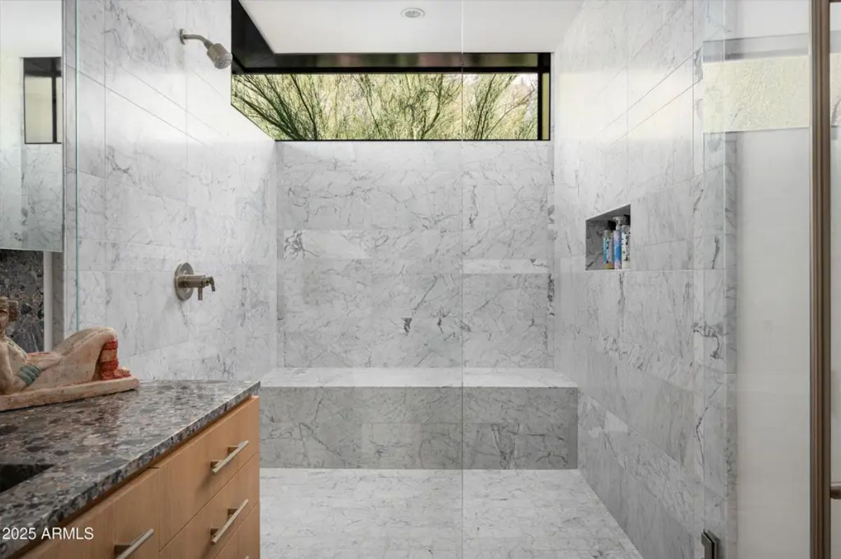 Luxurious walk-in shower with floor-to-ceiling marble, built-in seating, and a sleek glass enclosure. 