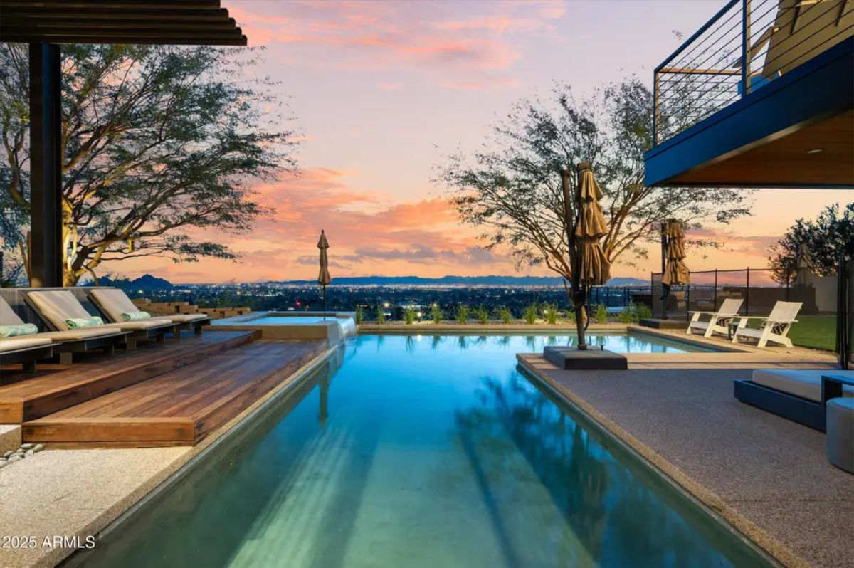 Stunning infinity pool reflecting a vibrant sunset with lush greenery and a luxury deck. 