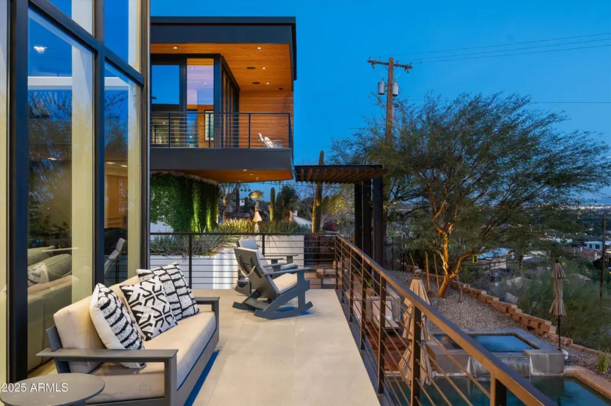 Scenic balcony with comfortable seating, a modern railing, and a picturesque view at dusk. 