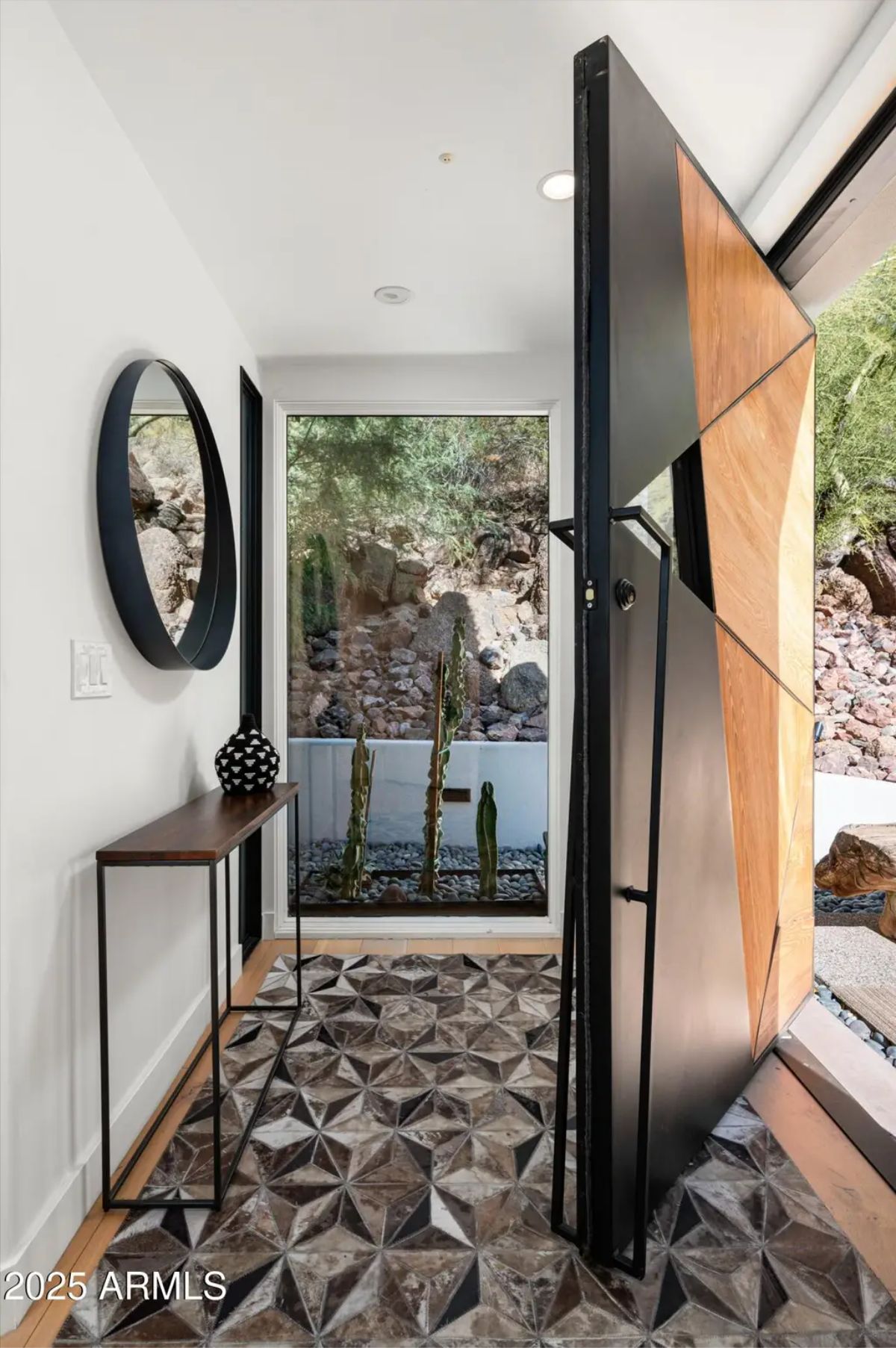 Bold geometric pivot door leading into a stylish foyer with a patterned tile floor and contemporary decor. 