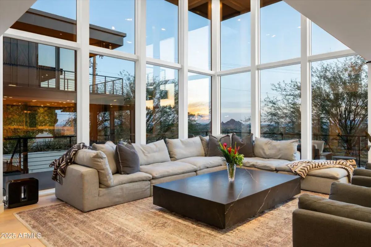 Expansive living room with a floor-to-ceiling glass wall, plush sectional sofa, and breathtaking mountain views. 