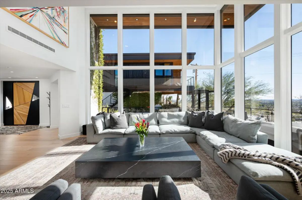 Sunlit sitting area with high ceilings, a black marble coffee table, and seamless indoor-outdoor integration. 