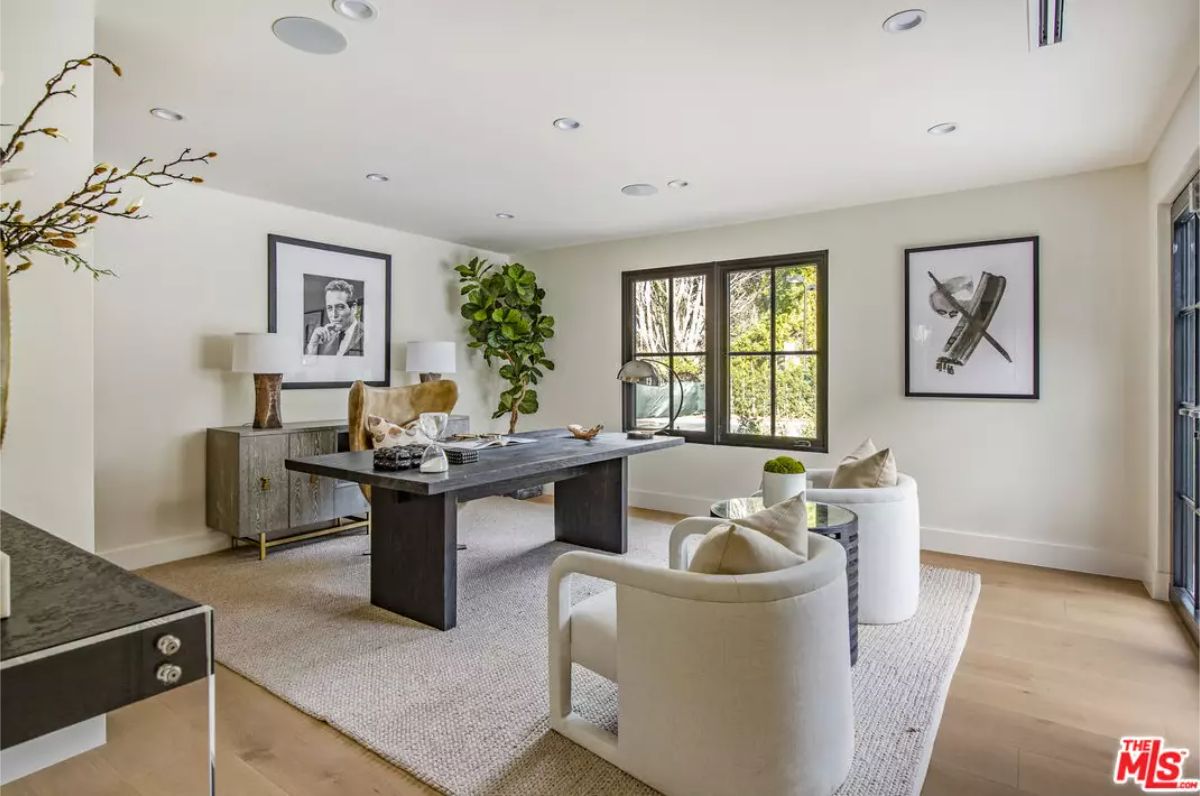 A dark desk sits centered between two curved white chairs.
