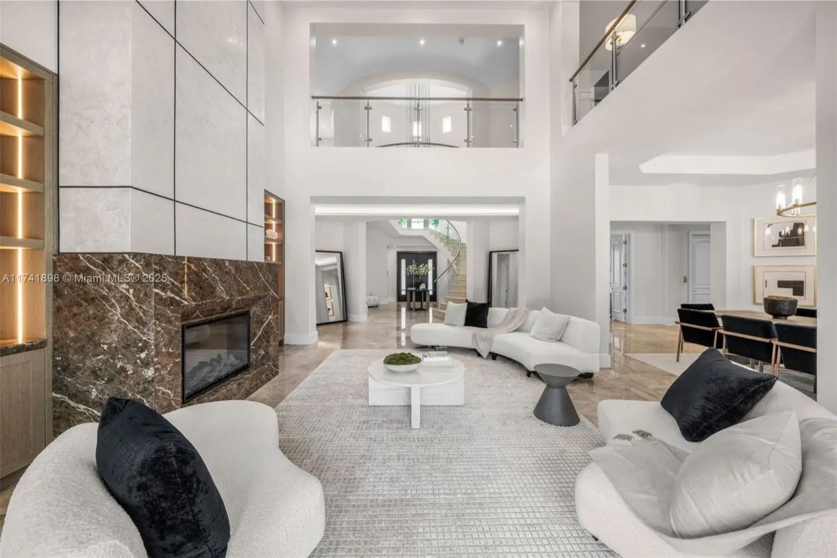 Tall ceilings frame a tiled fireplace with a second-floor overlook above.