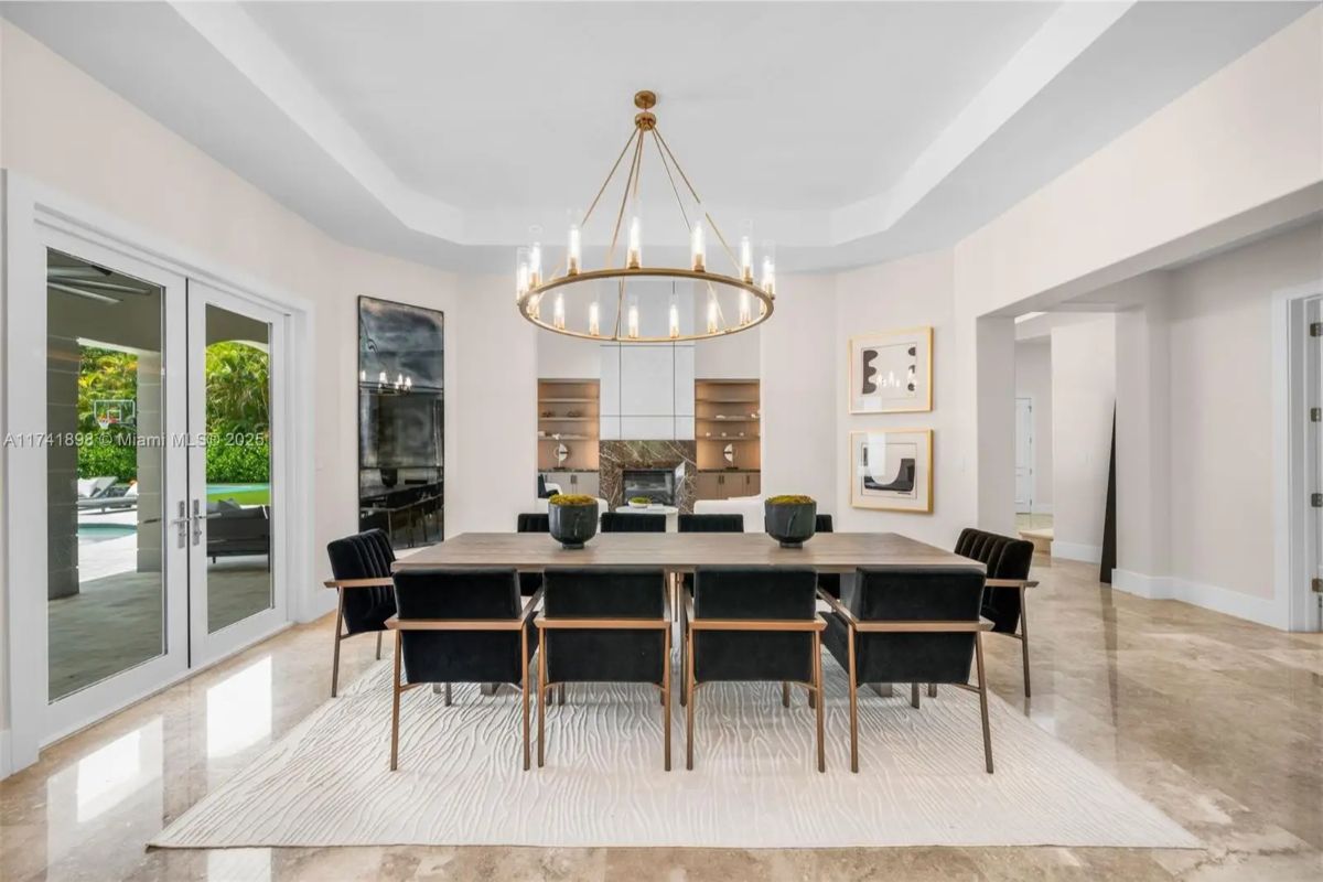 Black upholstered chairs surround a rectangular table beneath a circular chandelier.