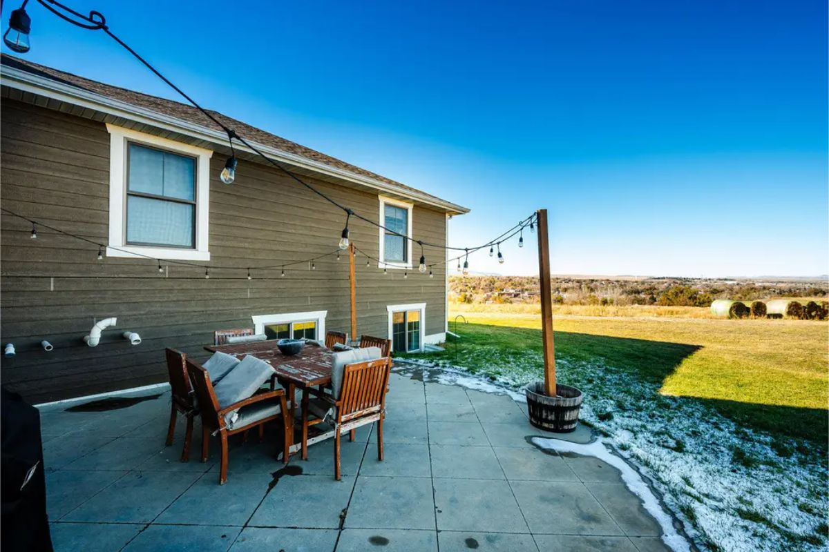 Concrete patio is furnished with a wooden dining table and chairs.