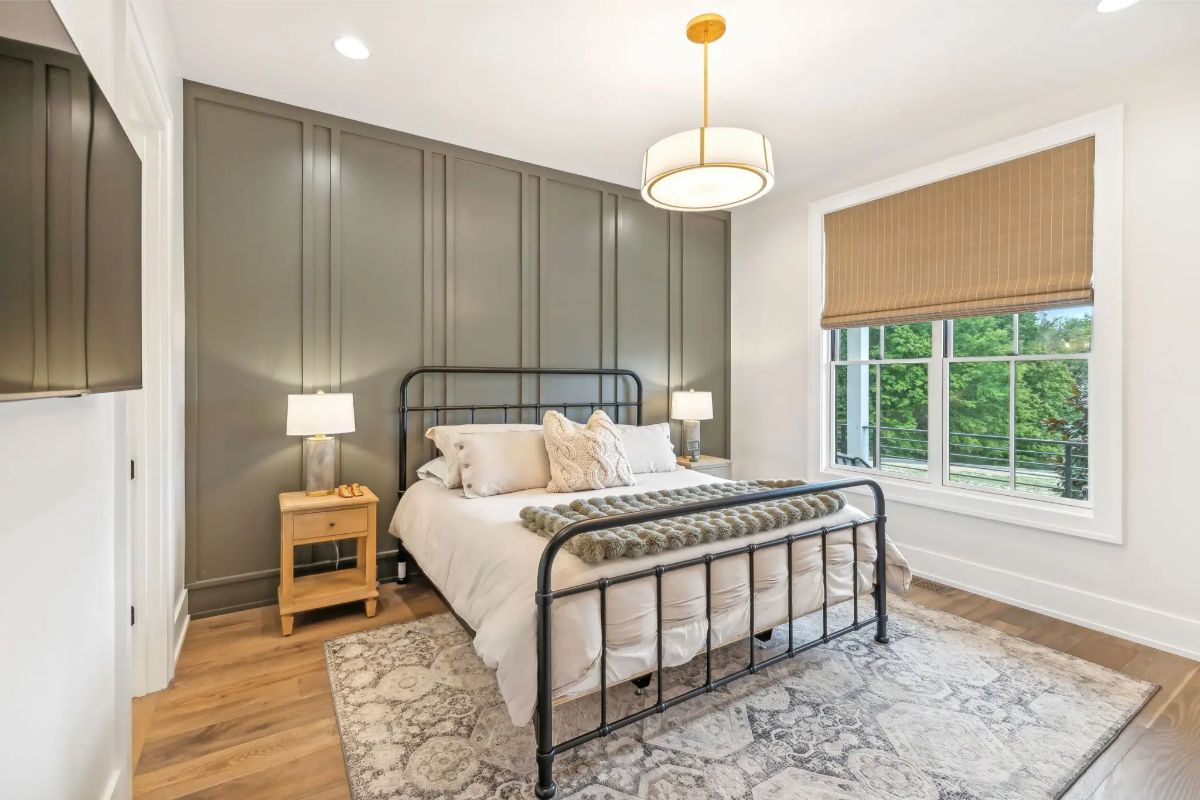 Guest bedroom with modern black metal bed frame, dark accent wall, and soft neutral decor. 