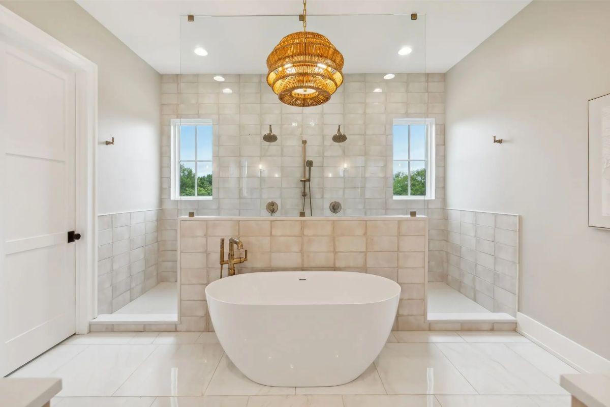 Freestanding tub centered in front of a tiled double shower with matching windows and a woven pendant light. 