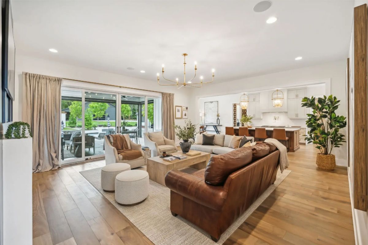 Open-concept living area with natural light, warm wood flooring, and seamless indoor-outdoor flow to the pool. 