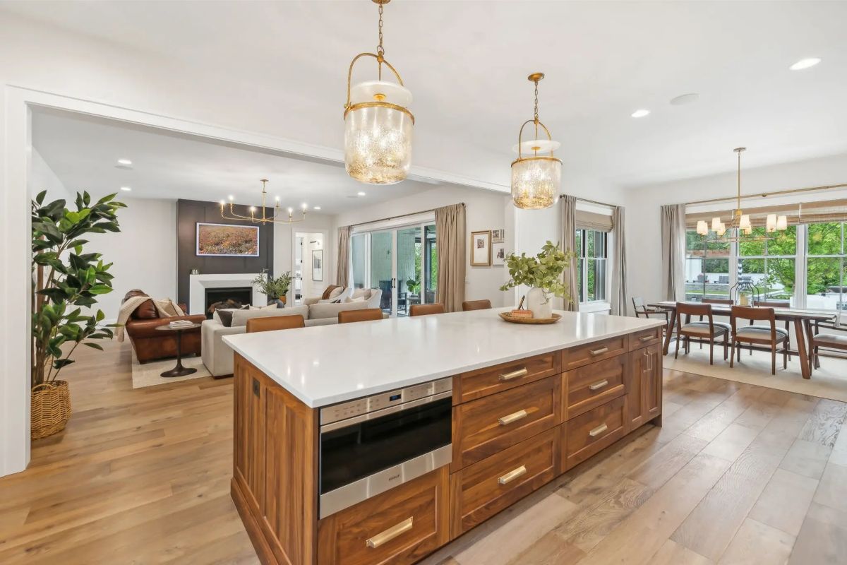 Kitchen island with waterfall countertops, warm wood cabinetry, and pendant lighting connecting to the open layout. 