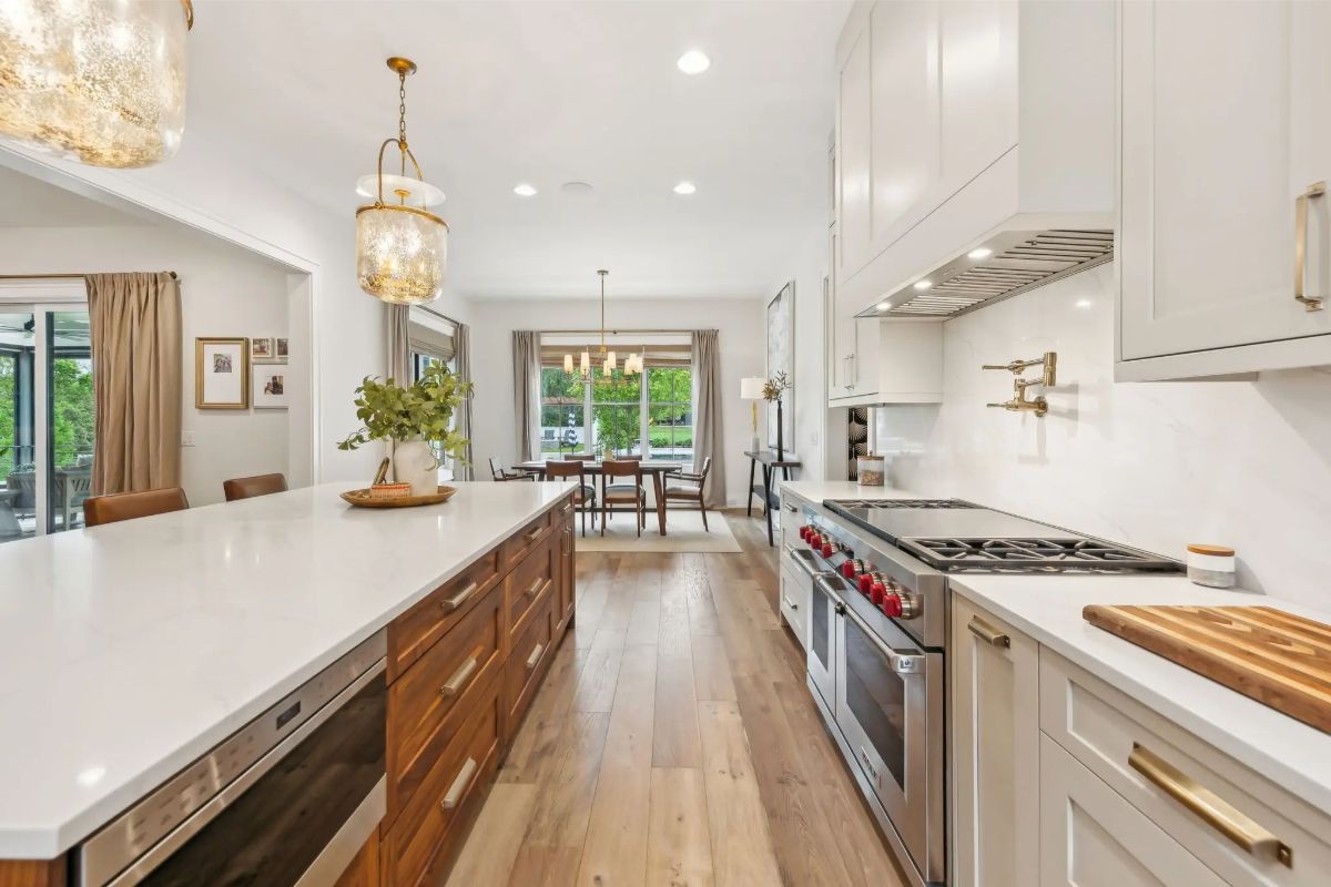 Sleek kitchen design with professional appliances, clean white cabinetry, and brass hardware. 