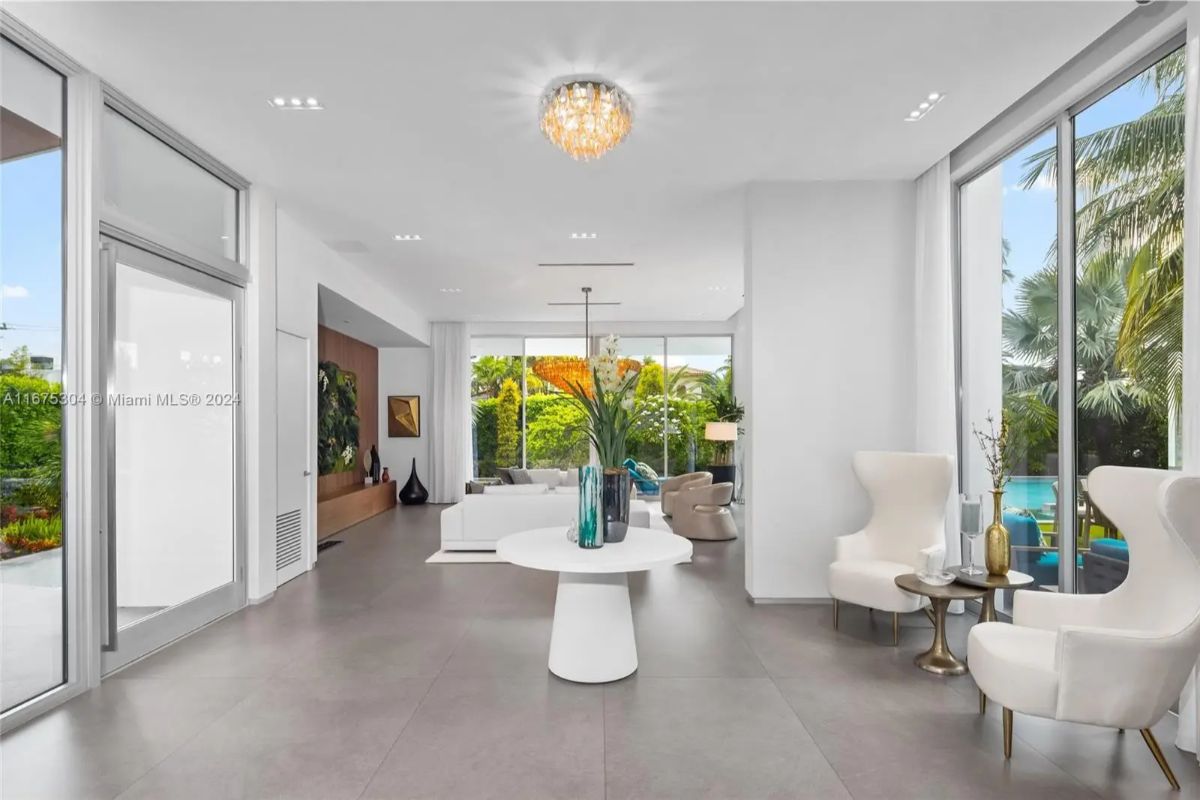 Spacious entry hall features large format gray tile floors and full-height windows on two sides.