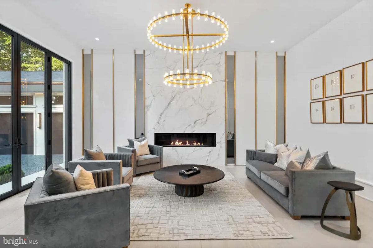 Seating area is centered around a black round coffee table and a sleek marble fireplace.