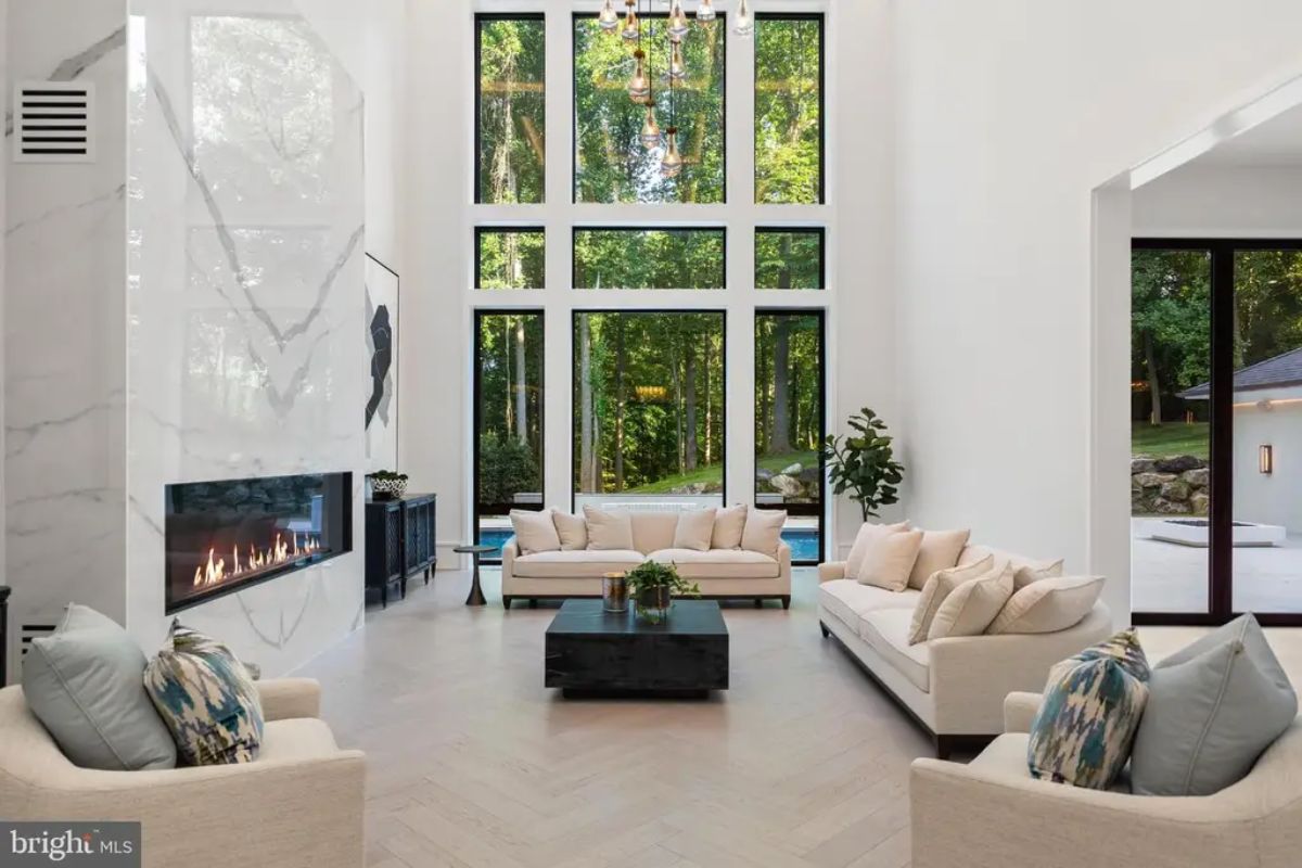 Spacious living area features a soaring ceiling and large glass windows overlooking the backyard.