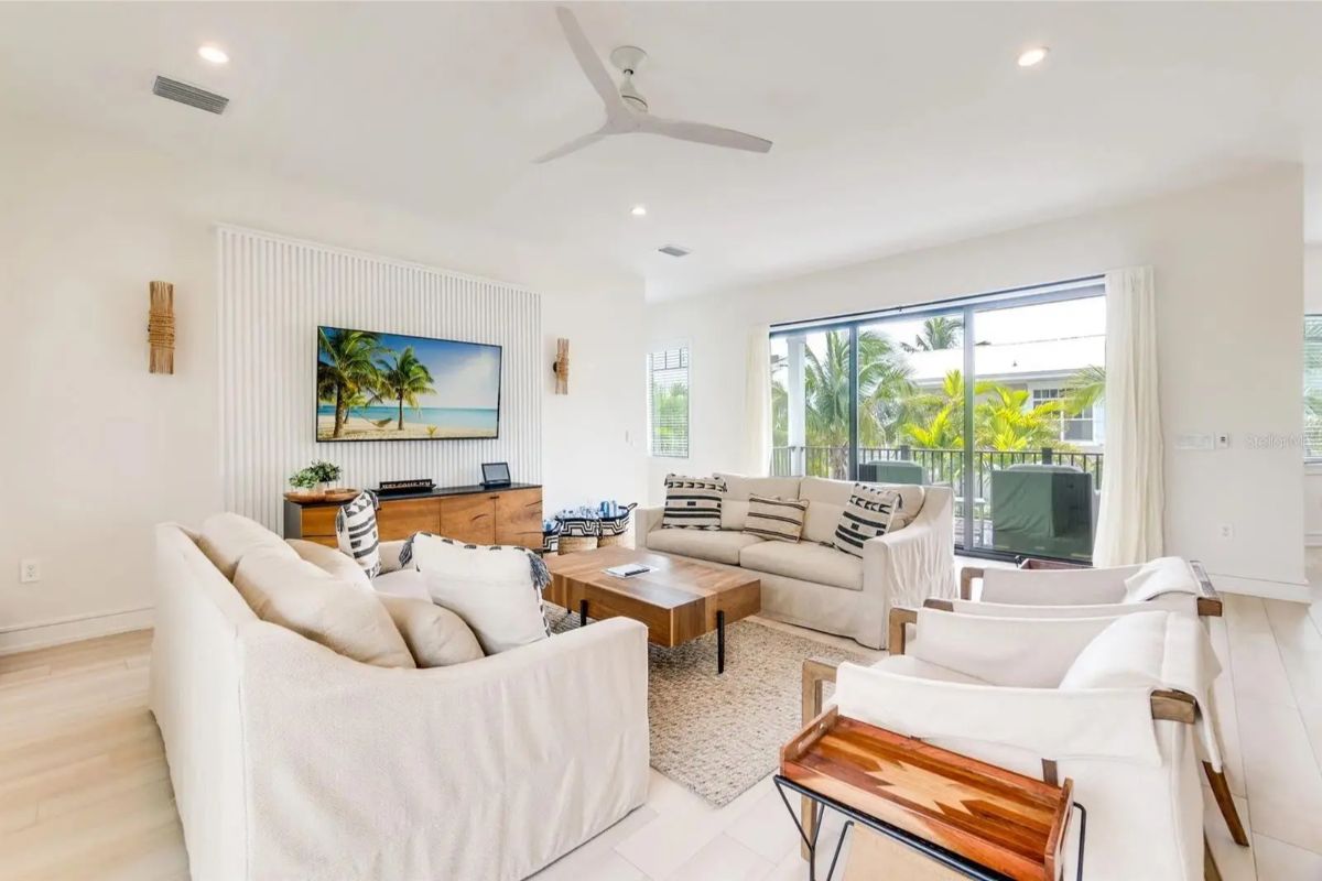 White-walled living room with light wood flooring has two sofas and two armchairs surrounding a wooden coffee table.