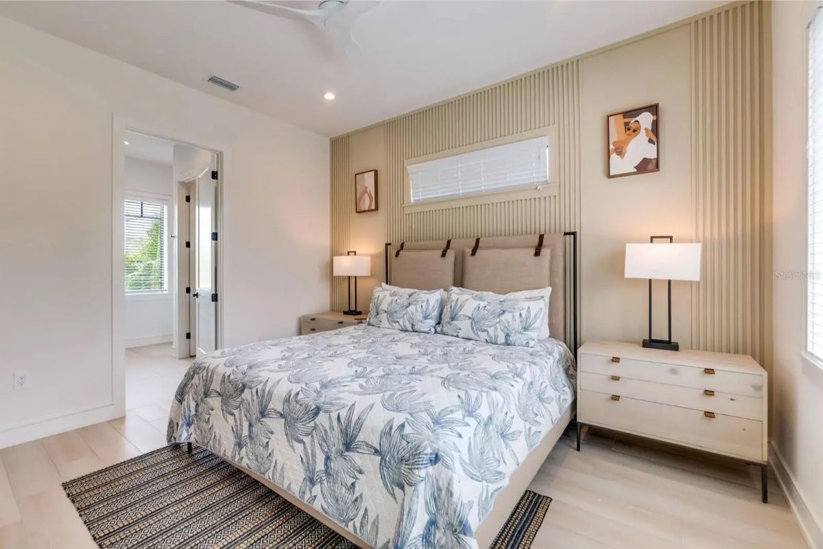 Bedroom features a queen-size bed with patterned bedding, positioned against a wood-accented wall with vertical paneling.