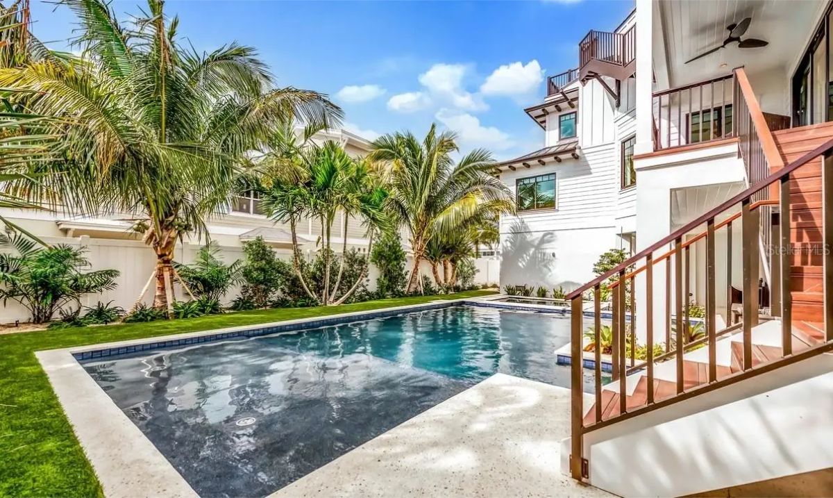 Backyard contains a rectangular in-ground pool surrounded by light concrete decking and grass.
