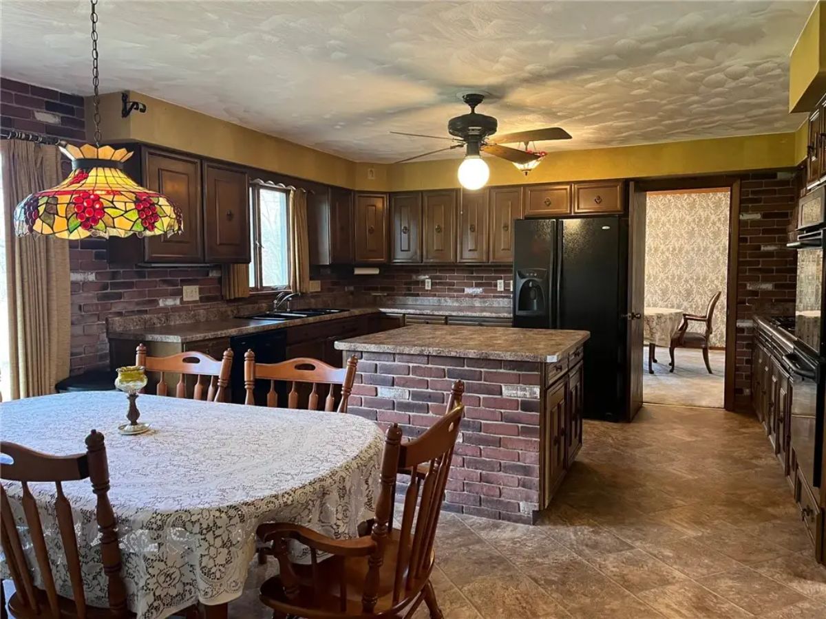 Spacious kitchen with dark wood cabinetry and exposed brick walls.