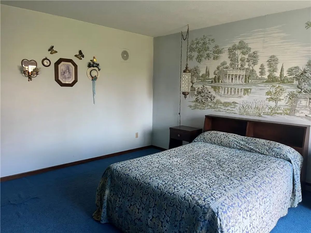 Cozy bedroom with a large bed covered in a blue patterned quilt.