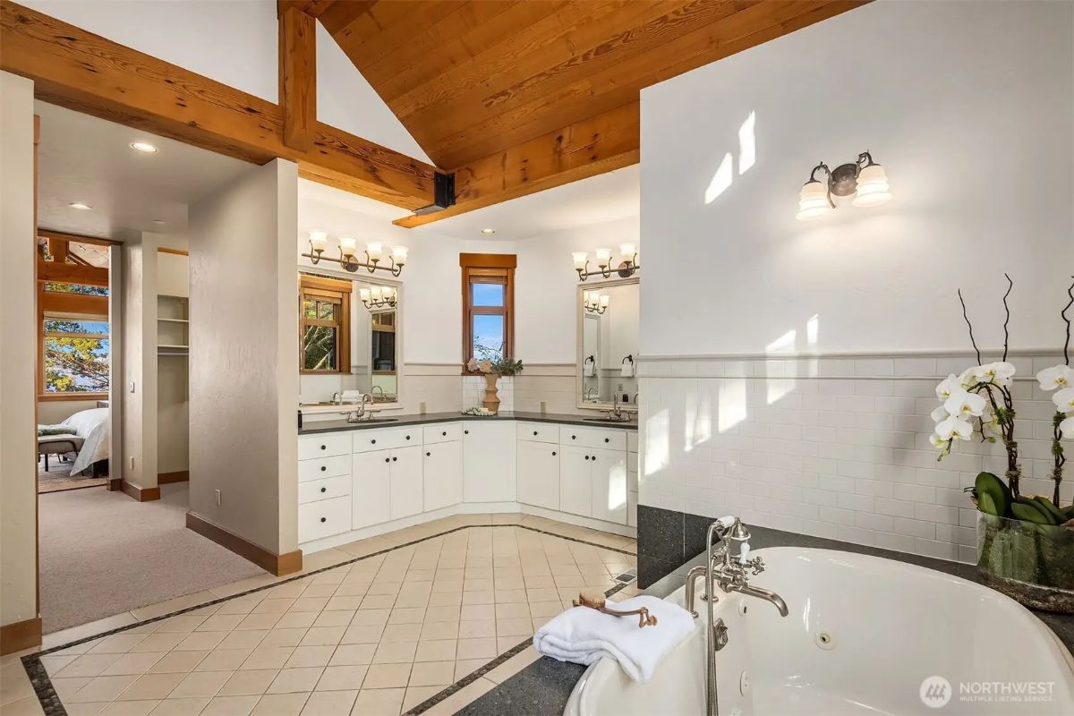 Spacious bathroom with double vanities, a soaking tub, and exposed timber beams for a rustic-modern charm. 