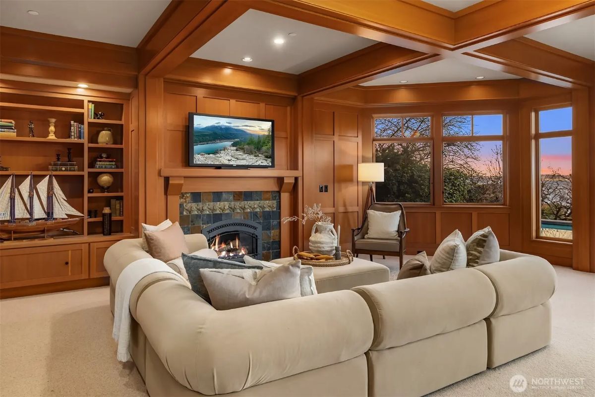 Secondary lounge with soft neutral tones, wood paneling, and a second fireplace for a relaxed, intimate setting. 