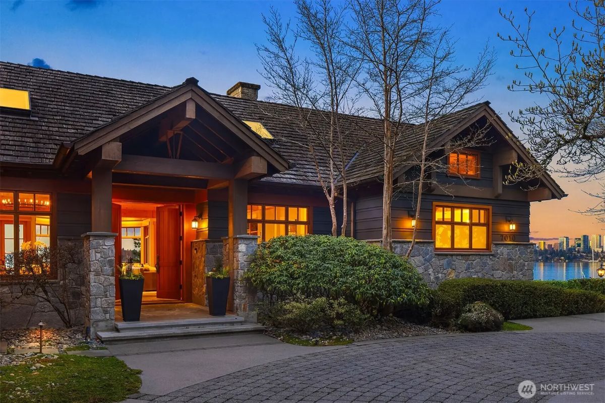 Warm and welcoming entryway featuring wood and stone elements, lit up against a scenic twilight sky. 