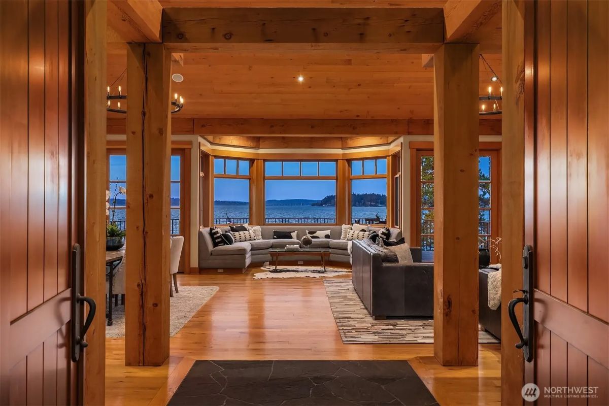 Grand interior view from the entrance showcasing wood beams and panoramic water views through large windows. 