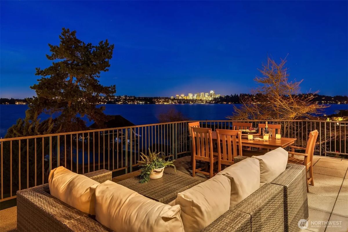 Elevated evening terrace with plush seating, dining setup, and glittering city views across the water. 