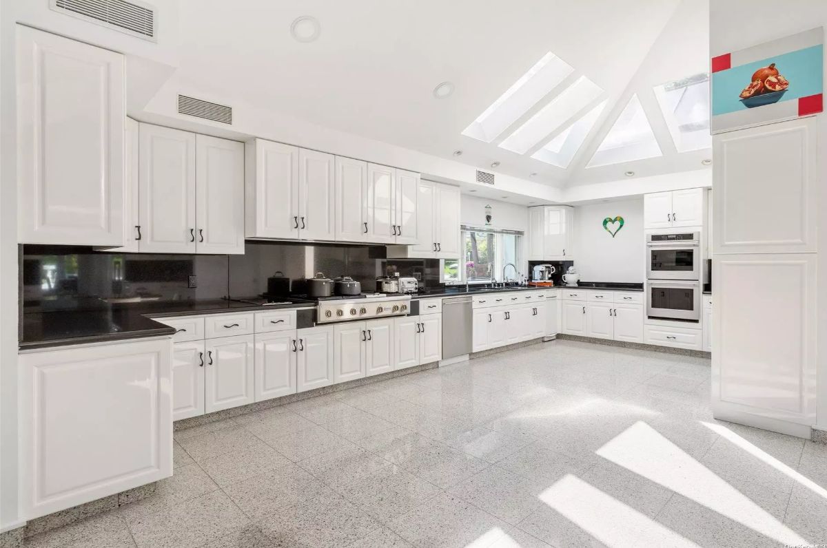 U-shaped layout includes extensive white cabinetry and black countertops.