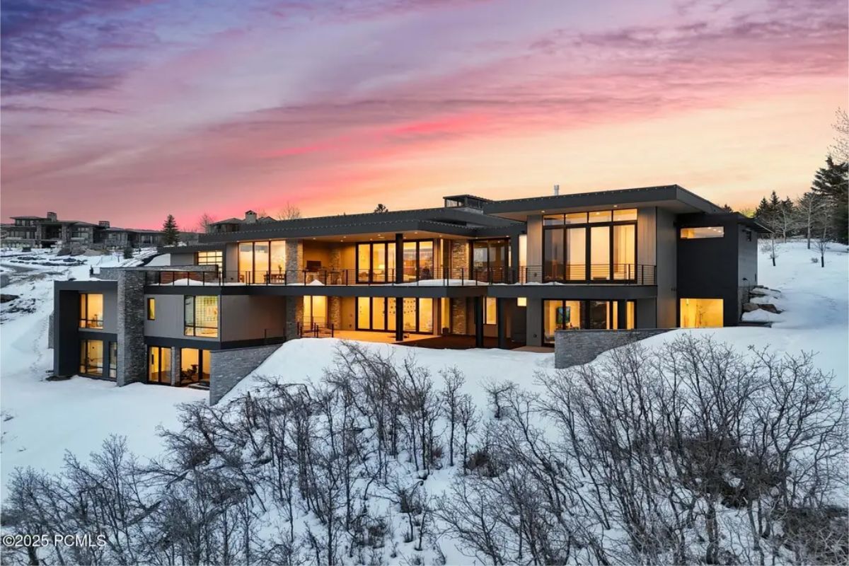 Expansive windows and sleek architecture seamlessly blend into the winter landscape, offering another view of the snow-covered home. 
