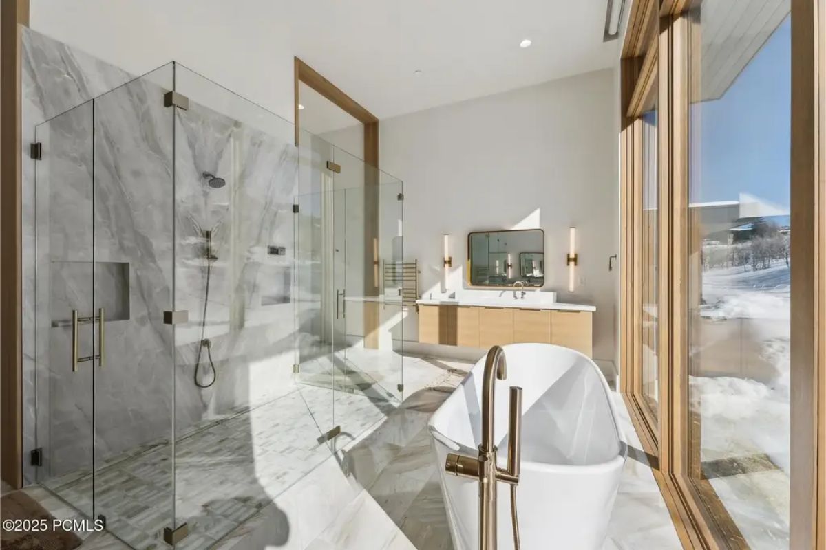 Luxurious bathroom with a glass-enclosed shower, a freestanding bathtub, and marble finishes throughout. 