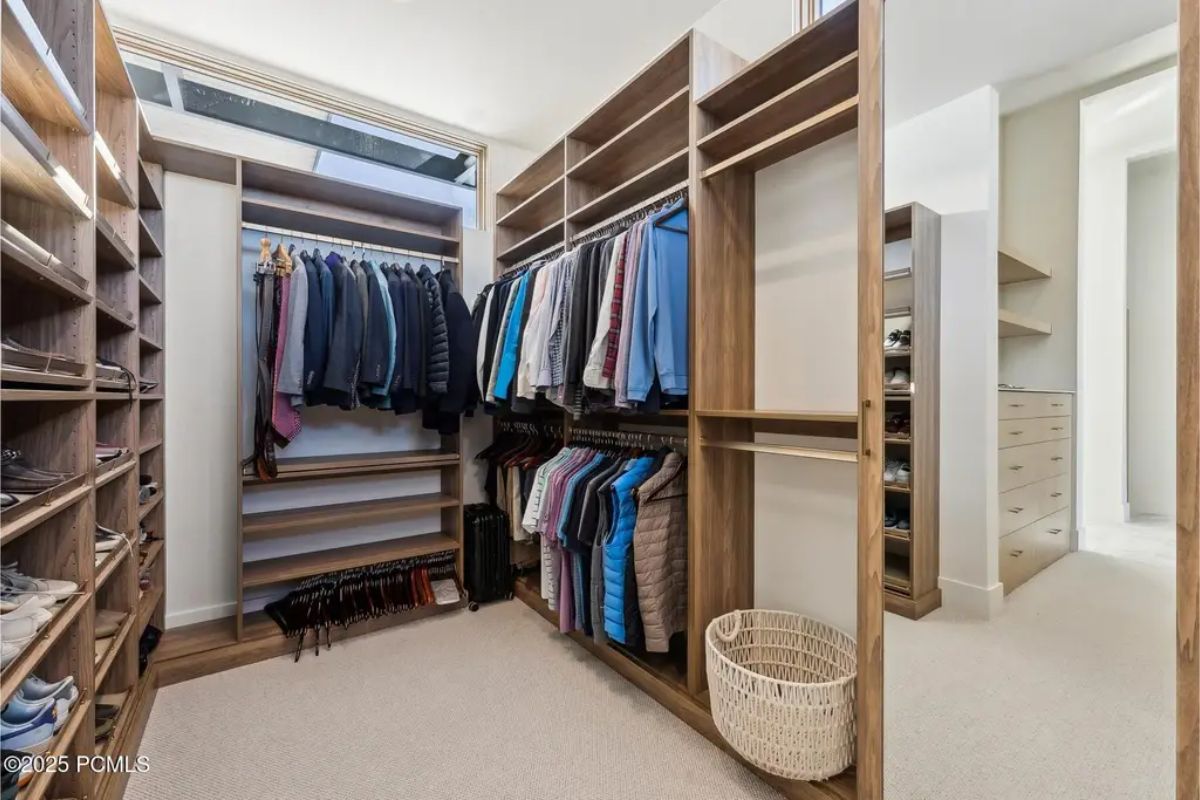 Well-organized walk-in closet with wooden shelving, ample storage, and a skylight for natural lighting. 