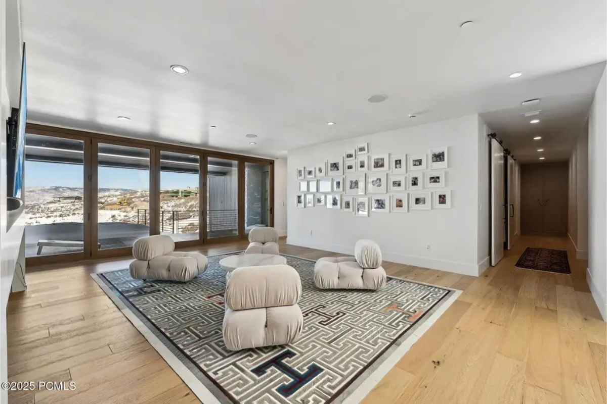Lounge area offers plush seating, a gallery wall of framed photos, and expansive windows that fill the space with natural light and mountain views. 
