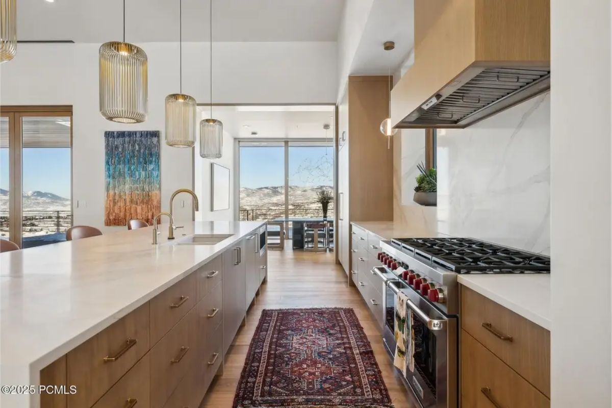 Sleek cabinetry and high-end appliances complement a long marble countertop in a beautifully designed kitchen. 