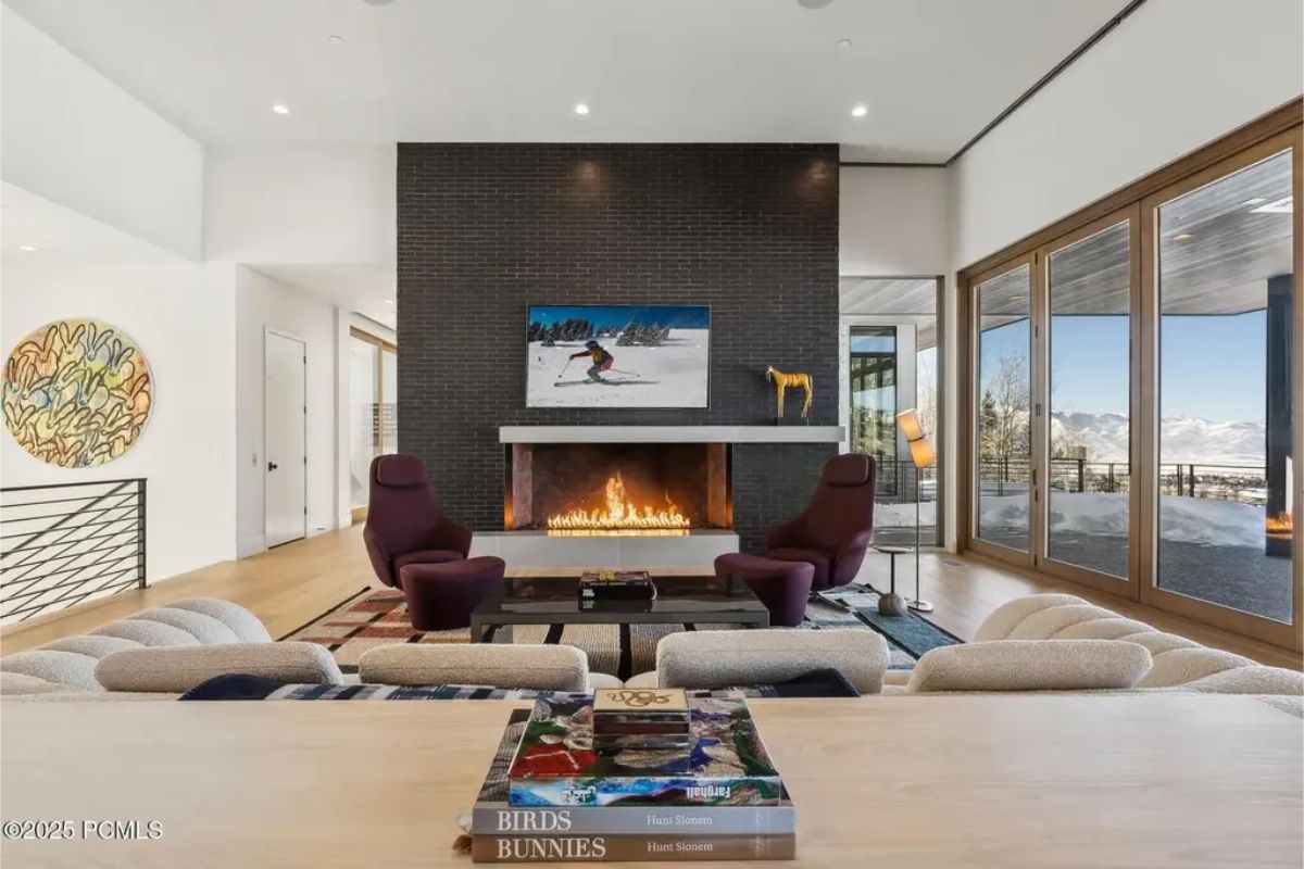 Elegant fireplace setting includes two deep red chairs and an open layout leading to an inviting outdoor deck. 