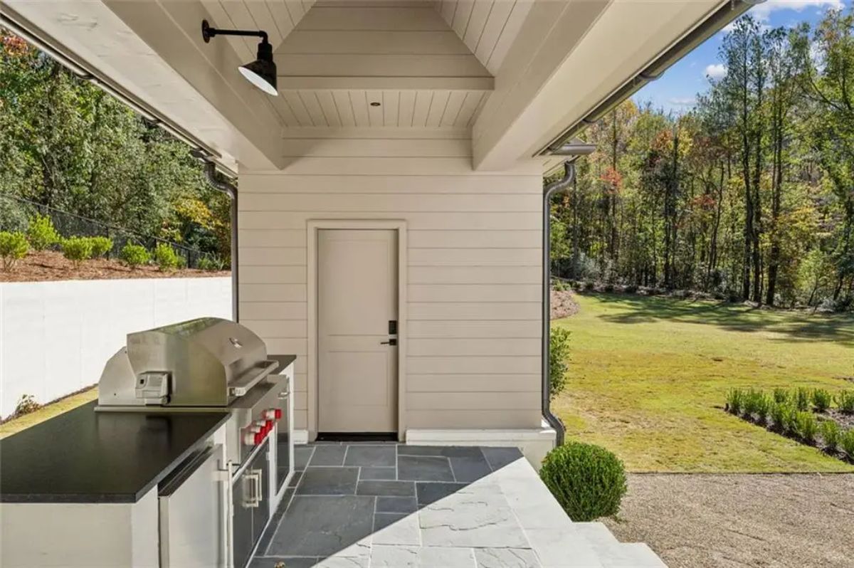 Built-in stainless steel grill and prep station sits under a covered outdoor kitchen space. 