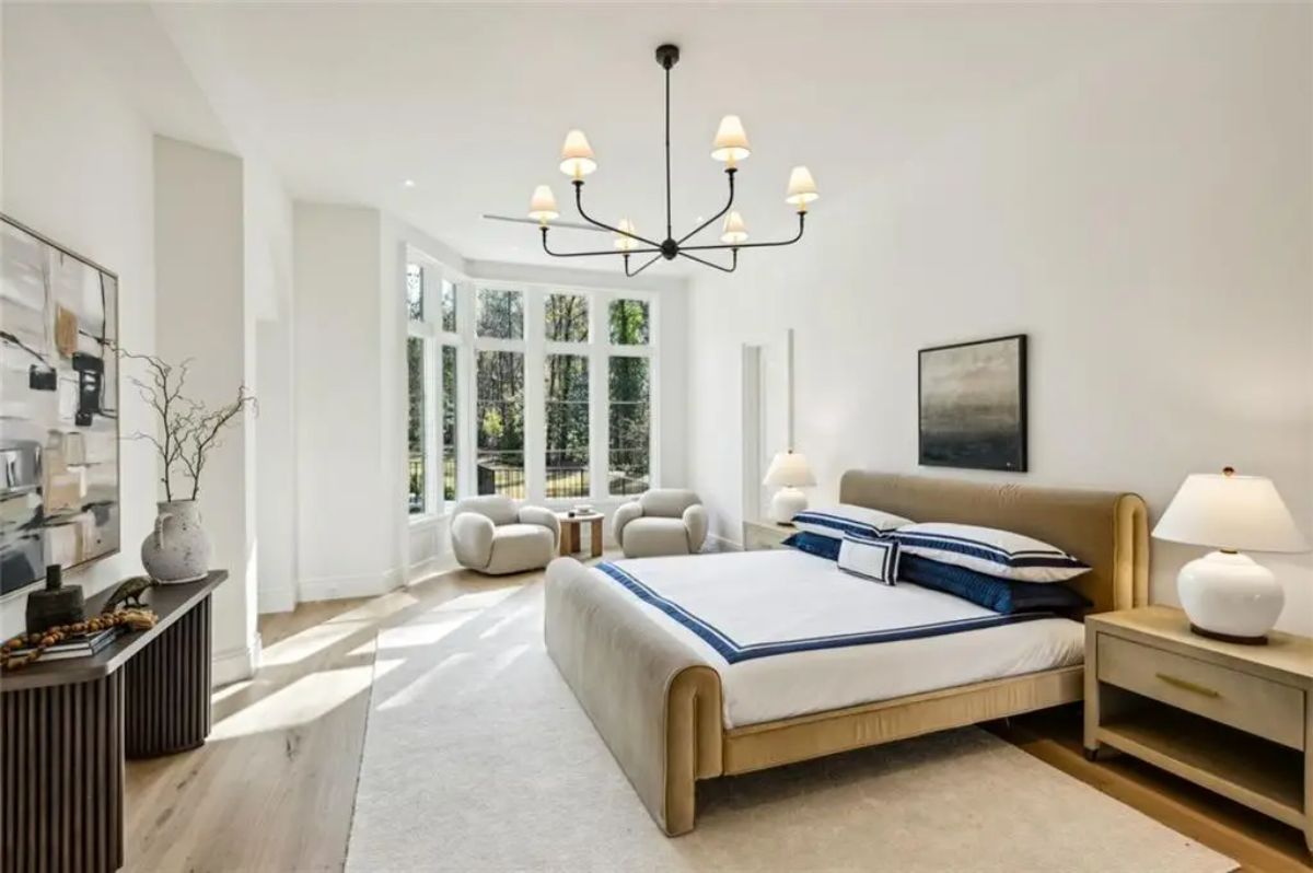 Serene primary bedroom with oversized windows and soft, neutral décor. 
