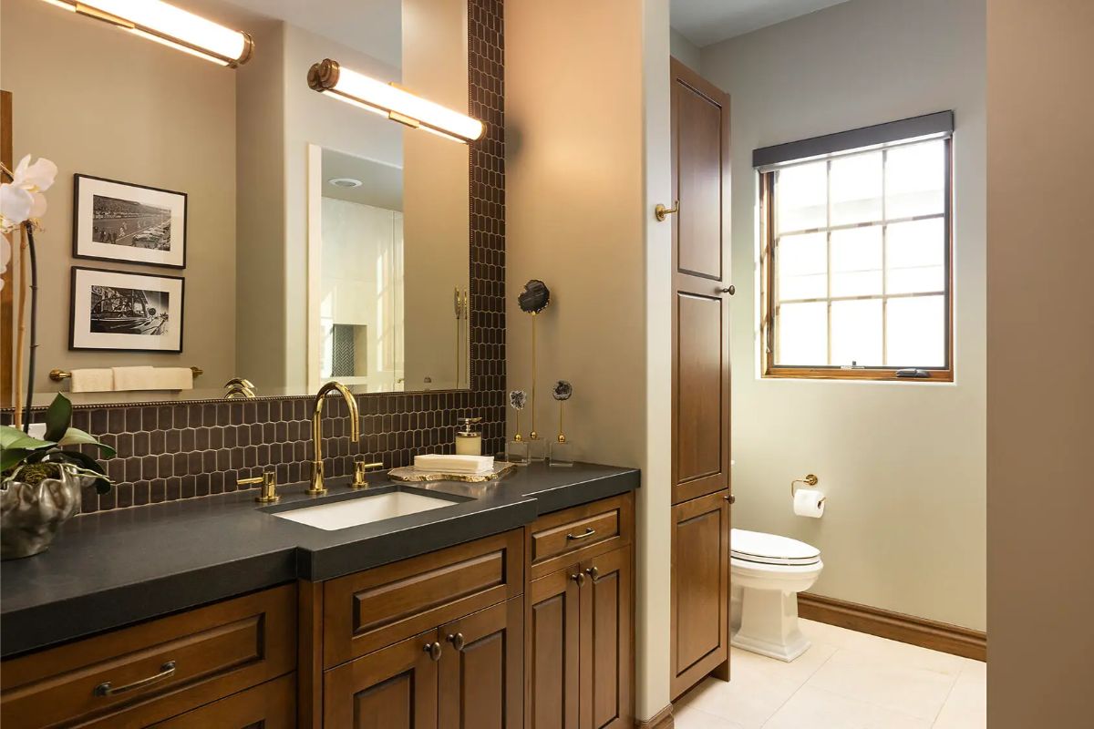 Single vanity sits below a large mirror with mounted lighting.