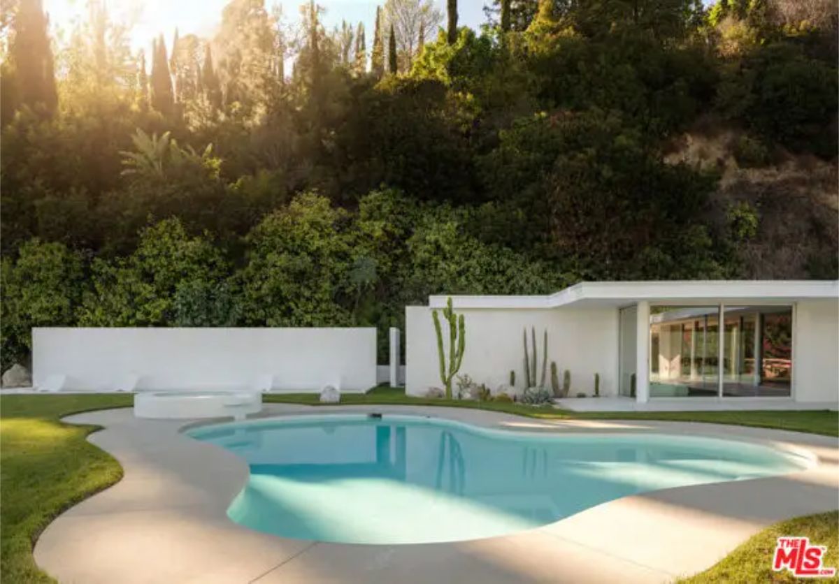 Private pool area with sleek white walls, desert landscaping, and a modern guesthouse. 