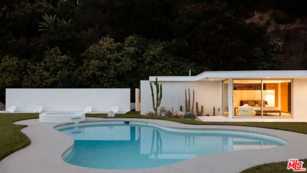 Twilight ambiance highlighting the warm glow of the guesthouse against the poolside backdrop. 