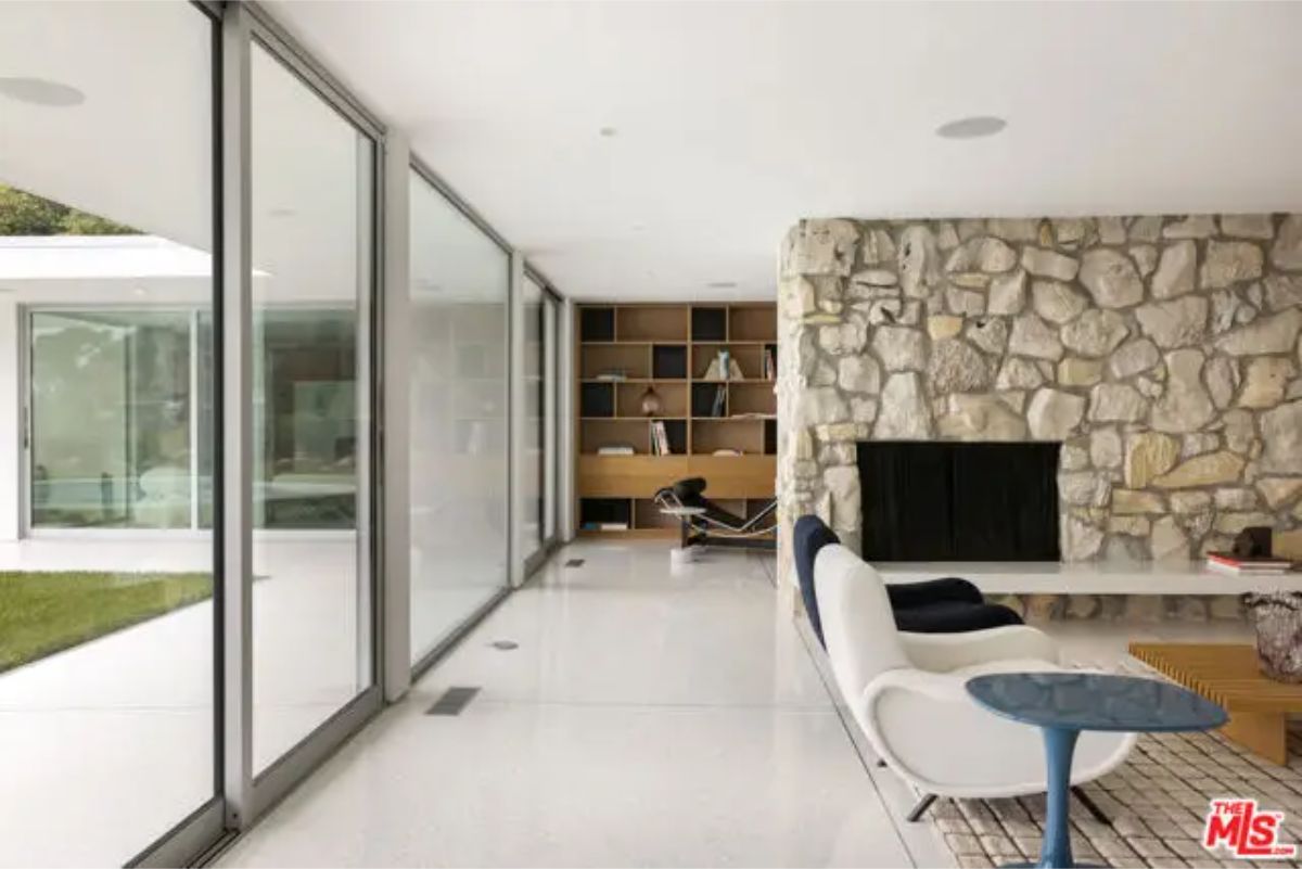 Glass-enclosed lounge corner with a built-in bookshelf and a picturesque view of the outdoors. 