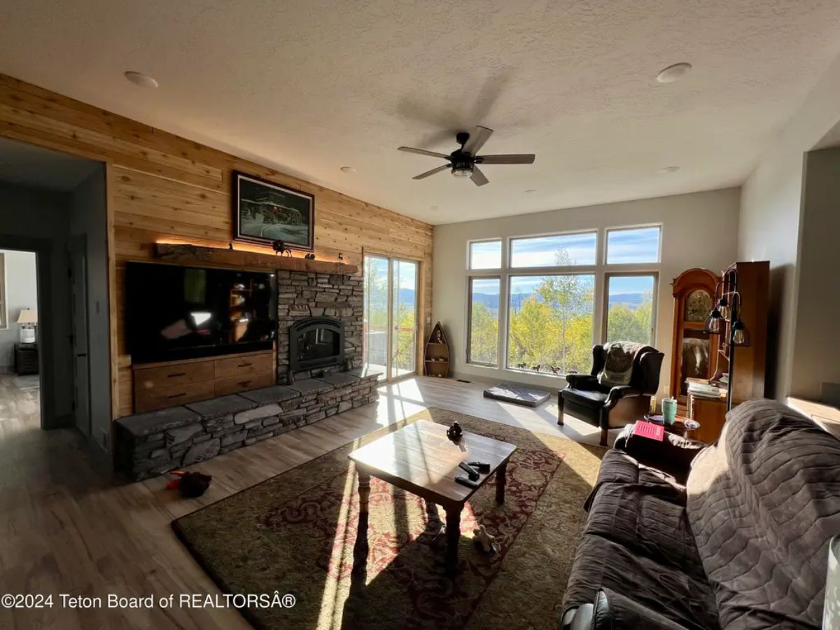 Stone fireplace with a wood-paneled accent wall houses a mounted television.